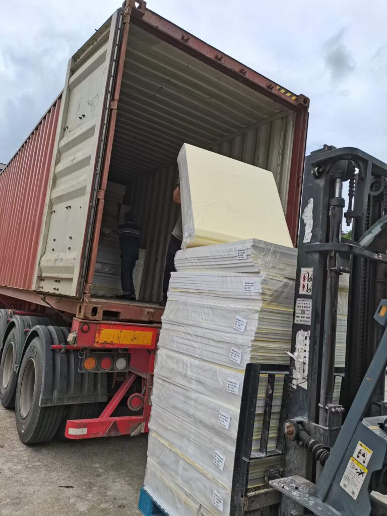 Loading white EVA foam sheets into a shipping container with a forklift