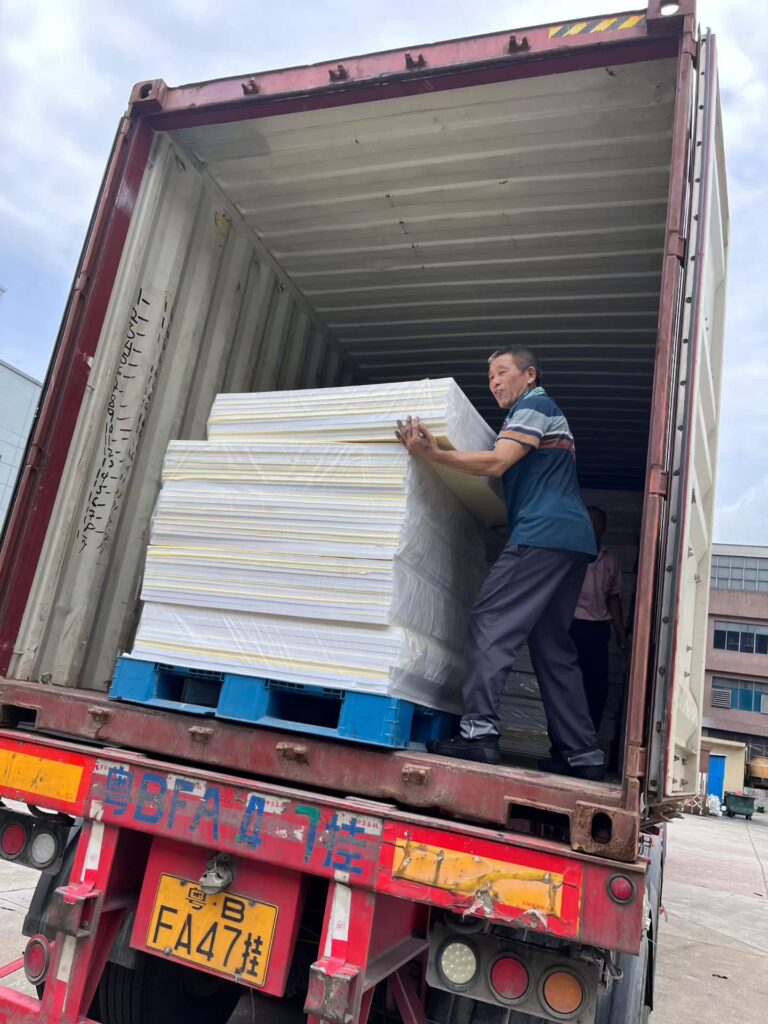 Worker loading white self-adhesive EVA foam sheets into a 40HQ container